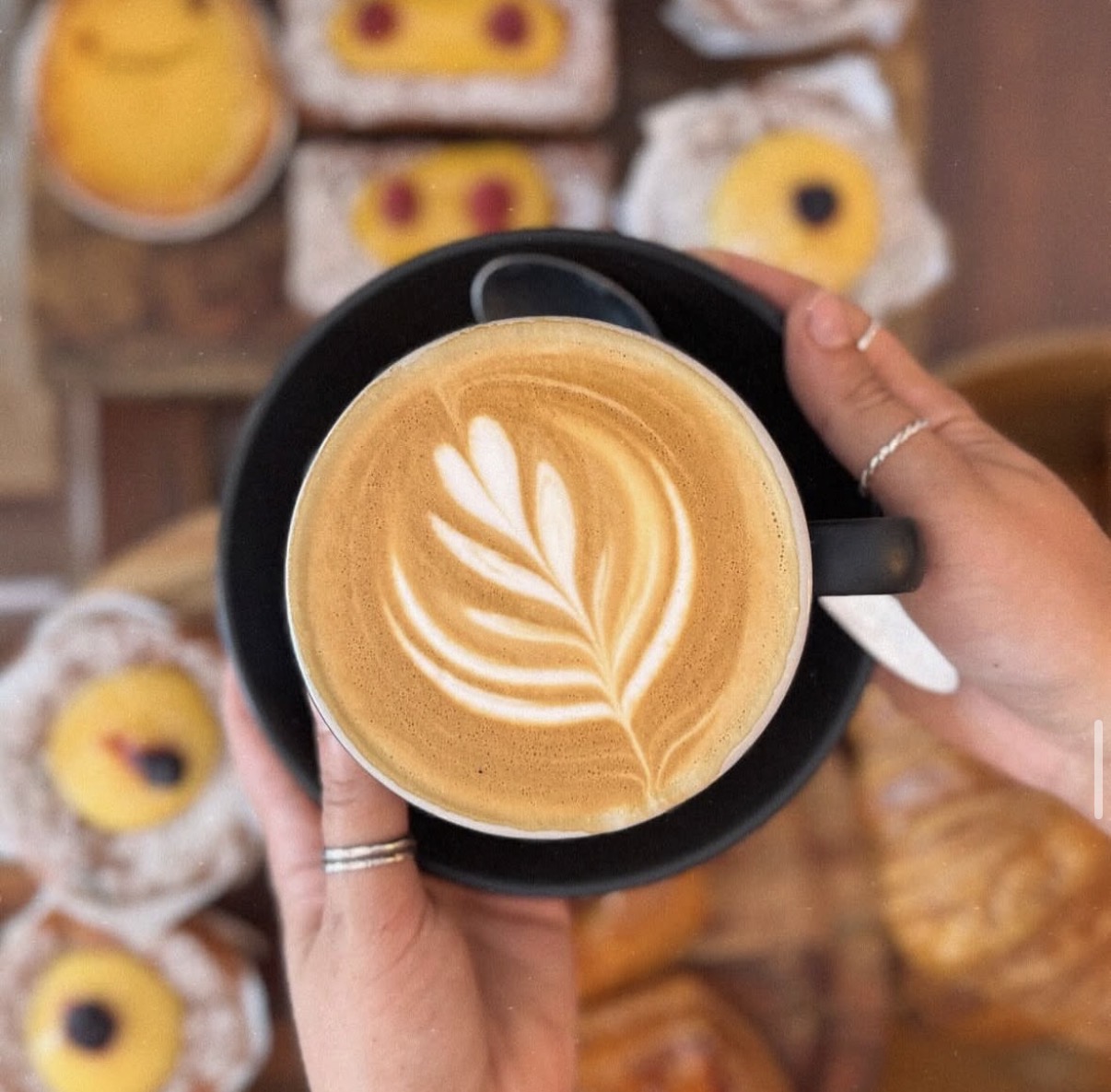Flat white with latte art held above the pastry cabinet