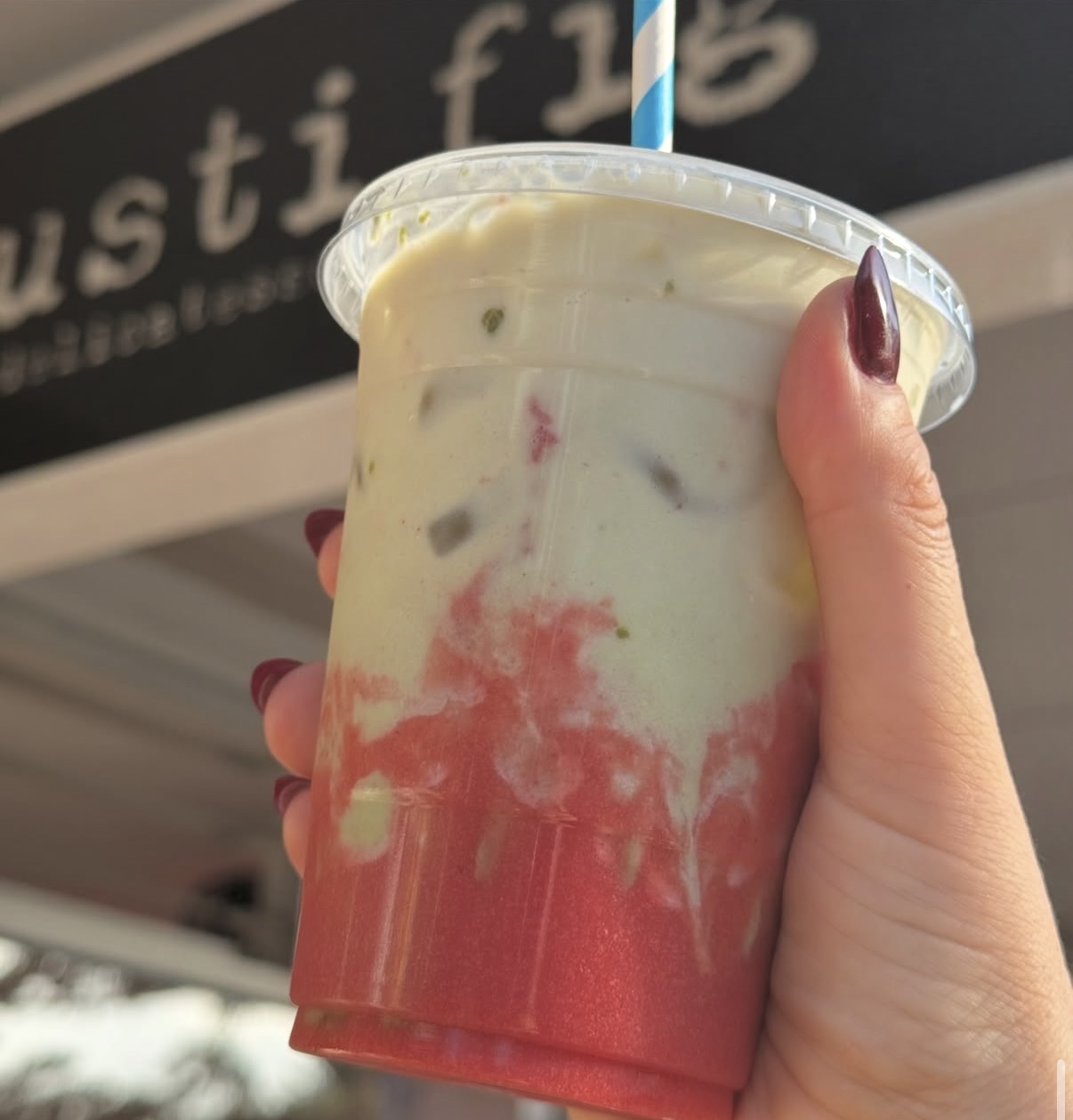 Iced strawberry matcha in front of the Rusti Fig sign